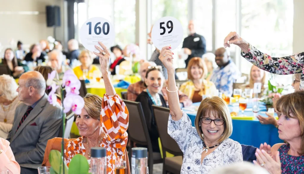 Supporters raising paddles during a Key Chorale fundraising event.