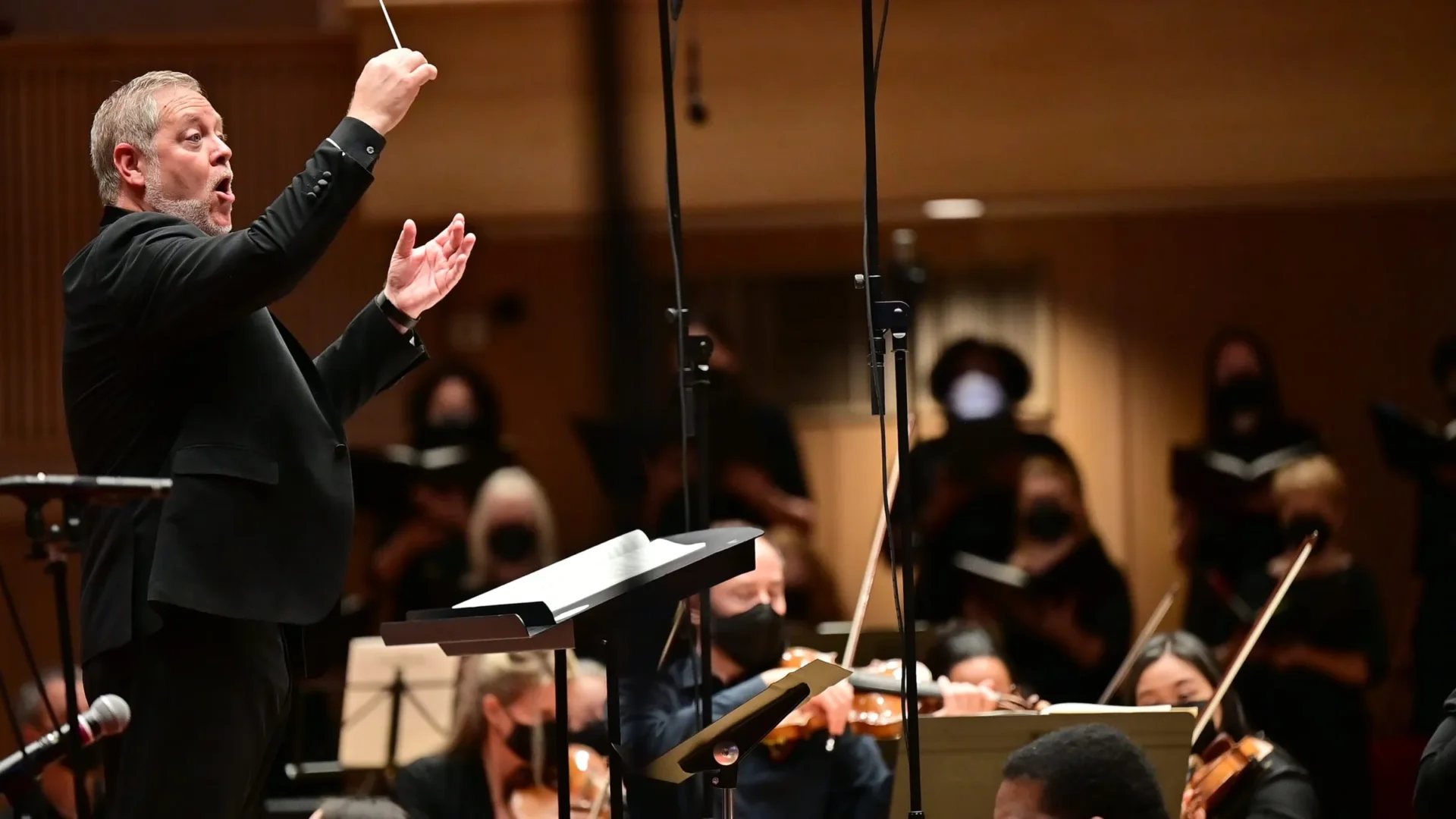 Conductor Joseph Caulkins leads Key Chorale and a live orchestra during a performance.